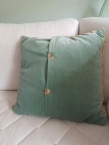 achterkant van geel gestreept kussen van restgarens in groen velours met een knoopsluiting