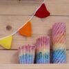 regenboog kaarsen voor een houten wand met een gehaakt vlaggenlijntje